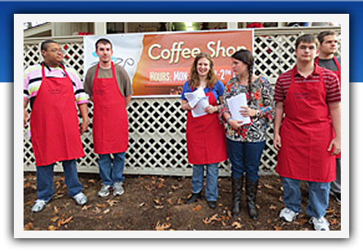 group of people wearing aprons in from of coffee shop
